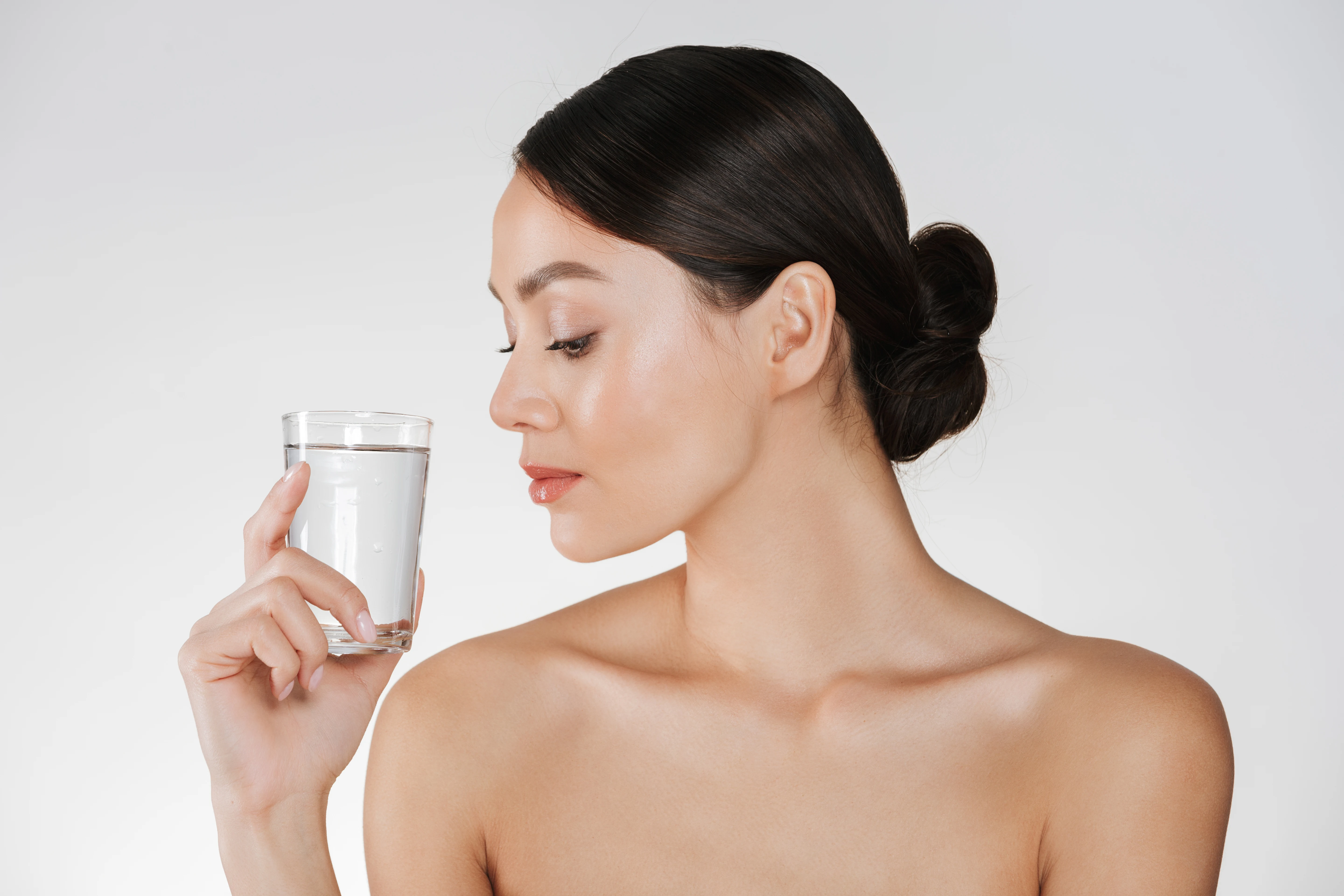 Woman holding and looking at a clear glass of water